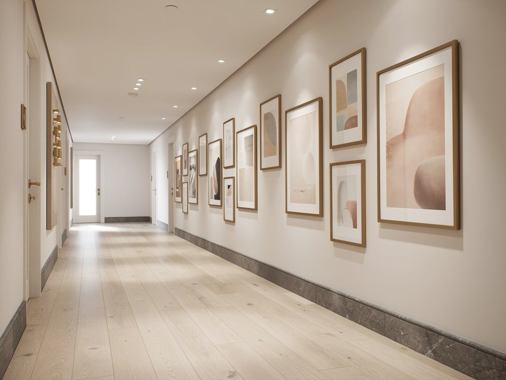 A curated wall of framed works in varied sizes, carefully spaced in a minimalist hotel corridor.
